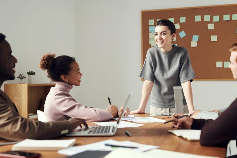 A woman stands confidently before a group, engaging them in a mentoring session during her internship